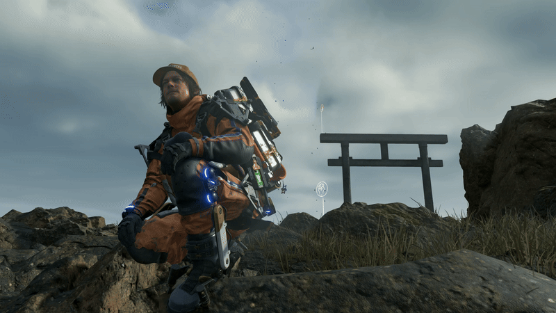 Personaje principal de Death Stranding sentado en una montaña